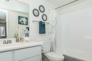 Modern apartment bathroom with shower tub, toilet, and mirrored sink vanity
