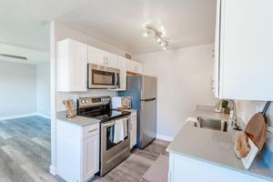 Open renovated kitchen with white cabinets and stainless steel appliances