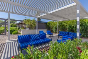 Outdoor shaded patio area with blue lounge couch seating around an electric firepit
