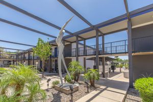 Outdoor modern art sculpture surrounded by an apartment complex walkway and overhead beams