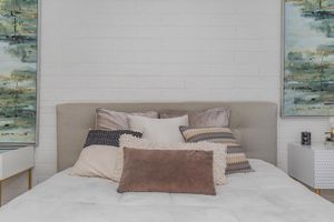 Elegant bed throw pillows on large bed in front of white brick wall
