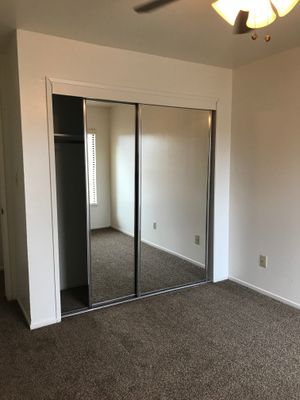 Vacant bedroom with sliding mirror glass closet doors