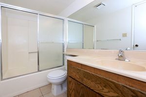 Vacant bathroom with wooden cabinets and sliding glass shower doors