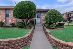 a large brick building with green grass in front of a house