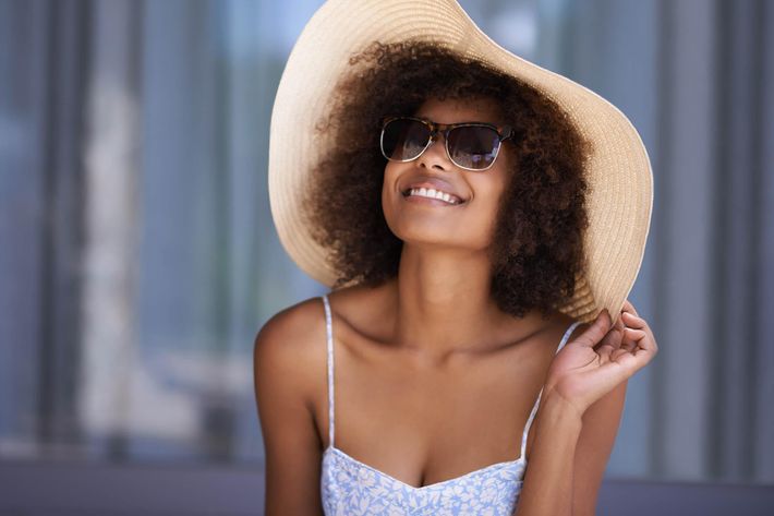 a person wearing a hat and sunglasses posing for the camera