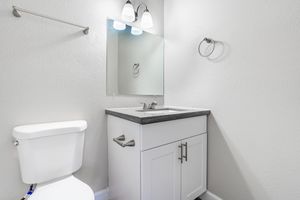 White cabinet vanity with mirror and toilet next to it