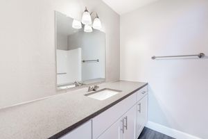 Quartz countertop bathroom sink vanity under a large mirror
