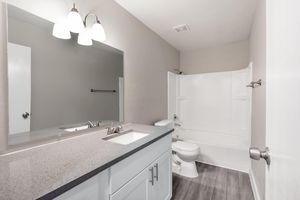 Bright renovated bathroom with granite countertops and a large mirror