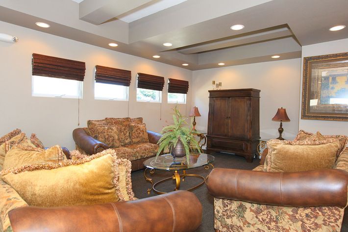 a brown leather couch in a living room filled with furniture and a window