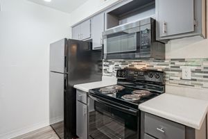 Kitchen equipped with black appliances and grey cabinets at Treehouse Apartments in Albuquerque, NM
