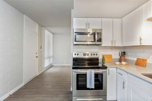 Open renovated kitchen with stainless steel appliances and white cabinets