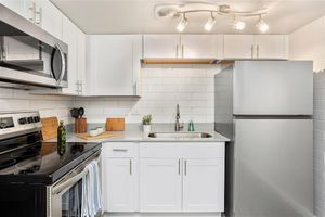 Open renovated kitchen with stainless steel appliances and white cabinets