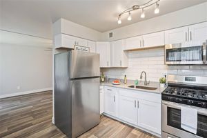 Fresh modern kitchen with white shaker cabinets, stainless steel appliances, and grey quartz counter