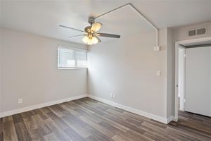 Large empty bedroom with view of a ceiling fan small window