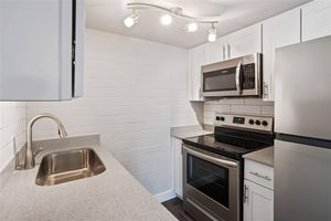 Galley way renovated kitchen with white cabinets and stainless steel appliances