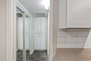 Hallway with mirrored closet doors and 4 white storage cabinets
