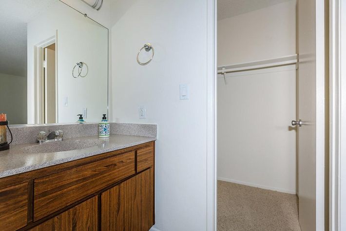 Bathroom sink with wooden cabinets and open closet door