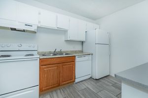 Kitchen with white cabinets, white appliances, and cherry wood sink cabinets