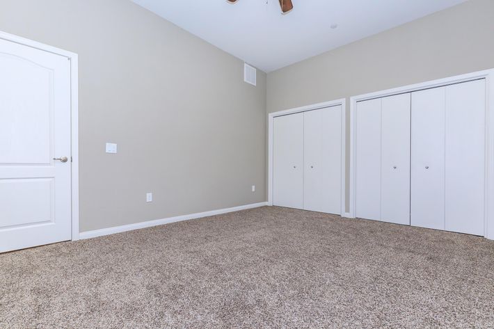 Vacant carpeted bedroom with closed closet doors