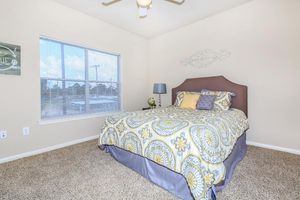 Furnished bedroom with double bed, ceiling fan, and large windows