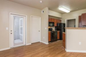 Living room with door to private balcony/patio and view of kitchen