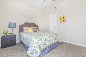 Bedroom with double bed, nightstand, and tan plush carpeting
