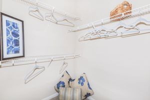 Walk-in closet with shelving, clothes hangers and decorative pillows