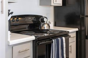 Close up of a black stovetop with a tea kettle on the burner