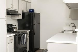 Bright kitchen space with white cabinets, black appliances, and silver finishes