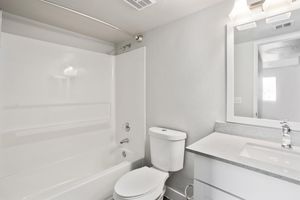 Renovated clean bathroom with tub, shower, toilet, and makeup vanity